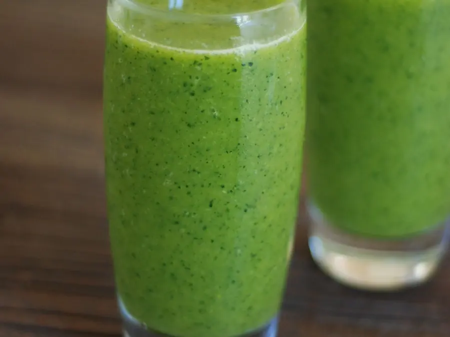 Twee glazen groene smoothie op een houten tafel