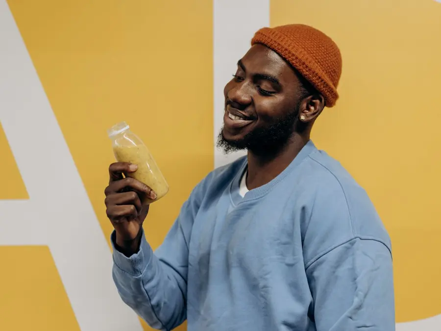 Lachende man drinkt een smoothie uit een flesje